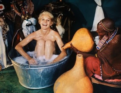 26 Mar 1965, Kenya, Africa --- Actress Carroll Baker goes native and enjoys it as a Masai tribeswoman adds more water to her tin tub. The American actress used the facilities in a tent during the filming of a United Artists releases, on location in Kenya. --- Image by © Bettmann/CORBIS
